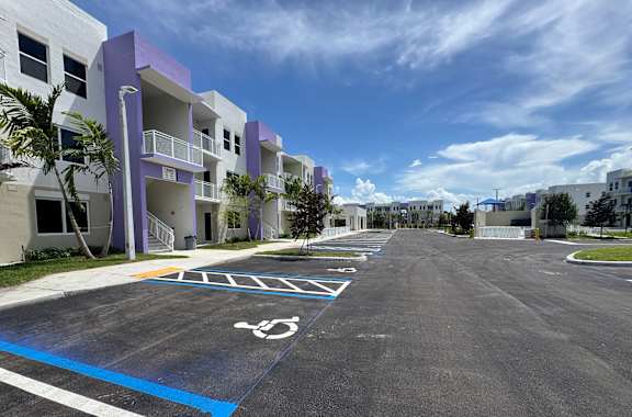 A parking lot with a handicap parking space in front of a white and purple building.