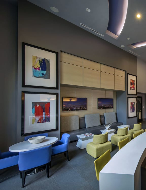 A modern cafe with blue and yellow chairs and a white counter. at West Park Apartments, San Diego