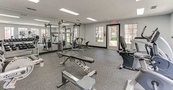A gym with a variety of equipment including treadmills, weights, and exercise machines.