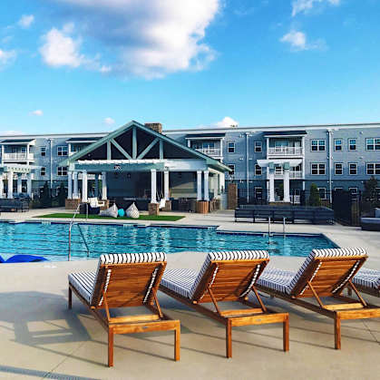 a large swimming pool with chairs in front of a building