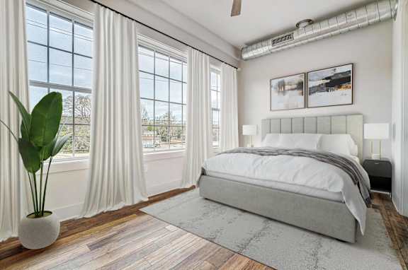 a bedroom with a bed and windows with white curtains