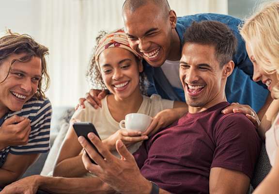 a group of people sitting on a couch looking at a cell phone