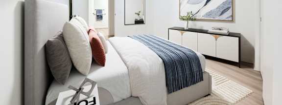 A bedroom with a bed, a mirror, and a painting on the wall.