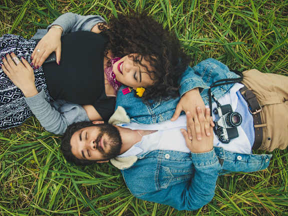 A couple is sitting on the grass watching a concert.