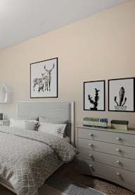A bedroom with a bed, dresser, and window with blinds.
