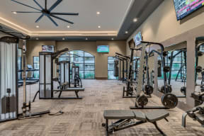 a gym with weights and cardio equipment and a tv