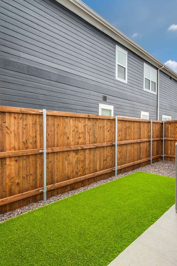 A backyard with a wooden fence and a green lawn.