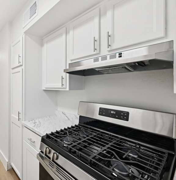 A modern kitchen with a stove top oven and white cabinets.