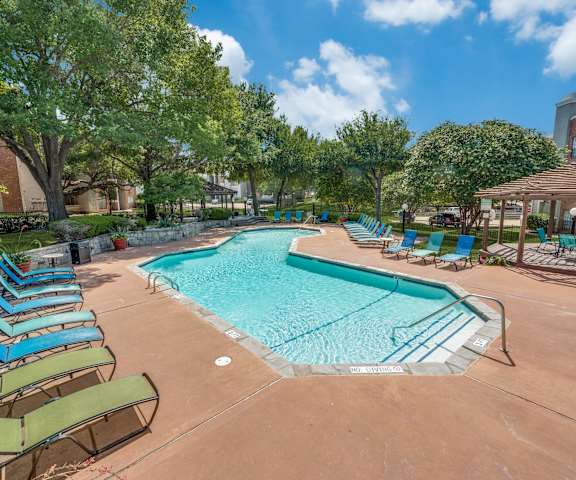 a resort style swimming pool with lounge chairs and umbrellas