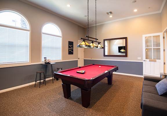 A pool table in a room with a mirror and a light fixture.