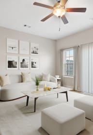 a living room with white furniture and a ceiling fan