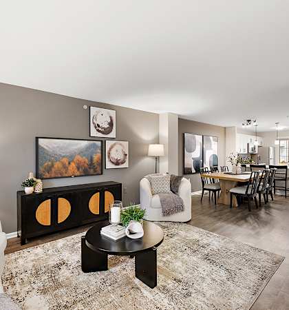 A living room with a grey couch, a coffee table, and a painting on the wall.