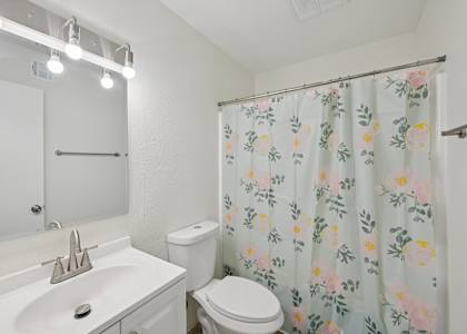 A white bathroom with a floral shower curtain.