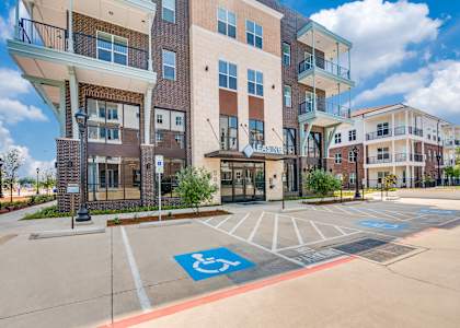 A parking lot in front of a building with a handicap parking sign painted on the pavement.