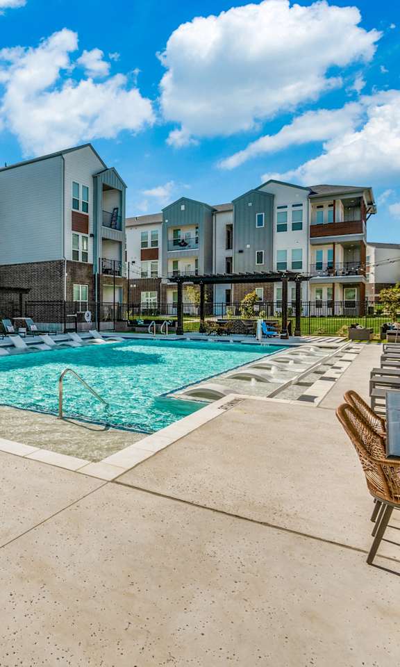 A large swimming pool surrounded by chairs and buildings.