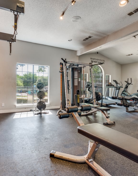 the gym has plenty of weights and cardio equipment and a large window at Foxborough Apartments, Irving, TX