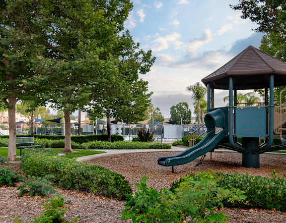A playground with a green slide and a brown pavilion.
