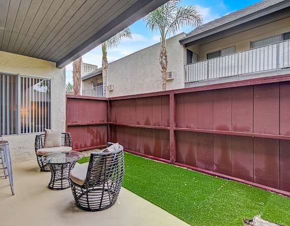 a patio with a table and chairs and a grassy area