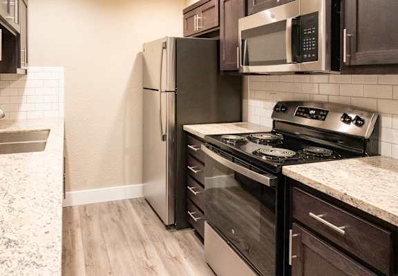 an updated kitchen with stainless steel appliances and wood flooring