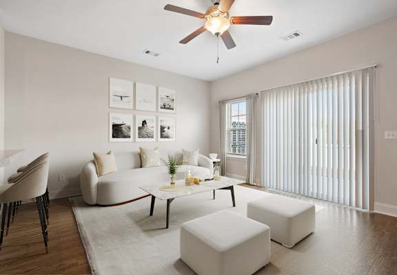 a living room with white furniture and a ceiling fan