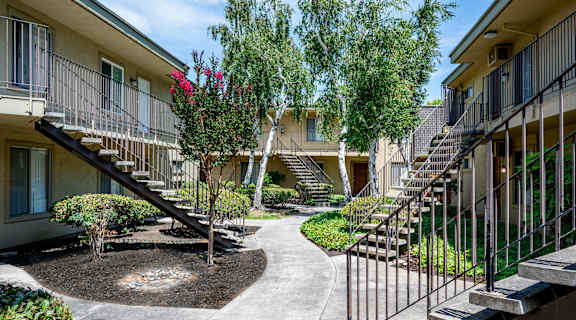 a courtyard with stairs and trees in front of an apartment building