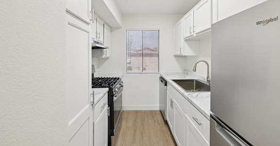 A kitchen with white cabinets and a Whirlpool refrigerator.