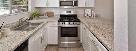 an updated kitchen with granite counter tops and stainless steel appliances