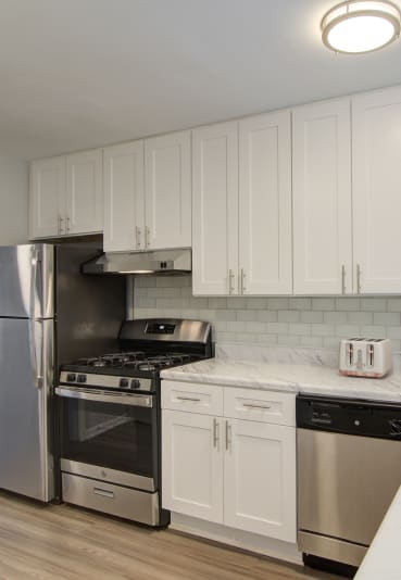 a kitchen with white cabinets and a bowl of fruit on the counter