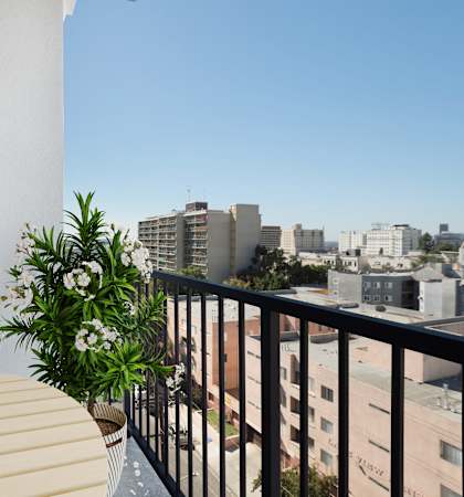 A balcony with a table and chairs overlooking a cityscape.