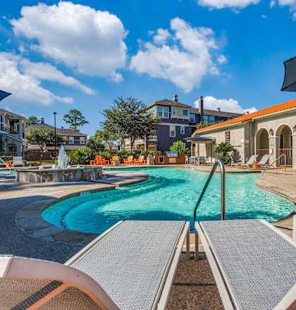 A swimming pool with a slide and sun loungers.