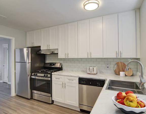 a kitchen with white cabinets and a bowl of fruit on the counter