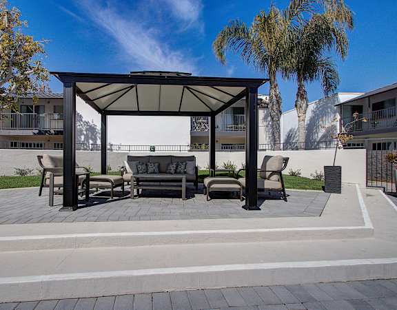 a patio with a couch and chairs under a gazebo