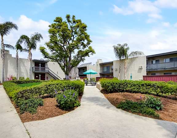 an umbrella sits in the middle of a garden at the whispering winds apartments in pearland,