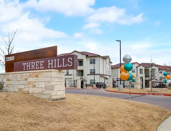a stone building with a sign that reads three hills apartments