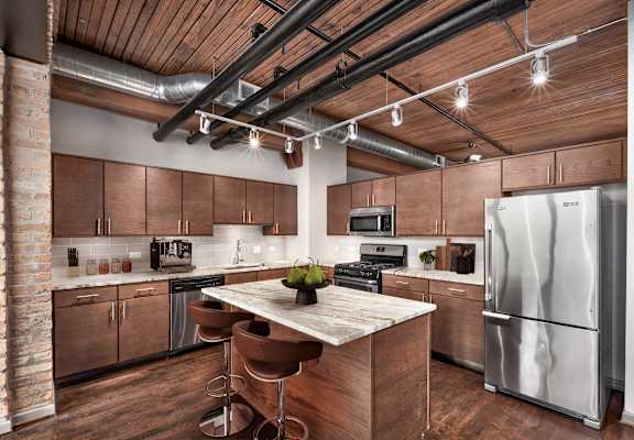 A modern kitchen with a wooden ceiling and stainless steel appliances.