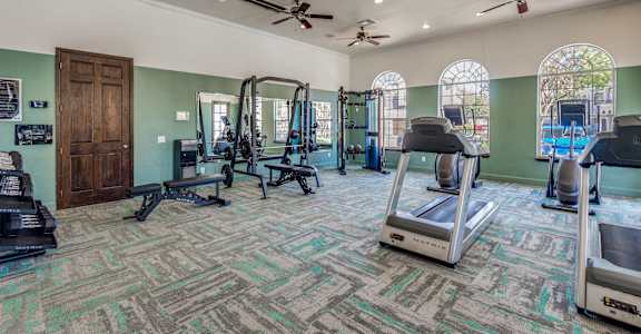 A gym with treadmills, weights, and exercise equipment.