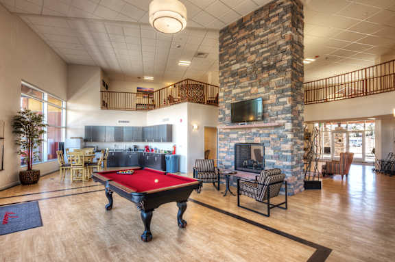 A room with a pool table and a fireplace.