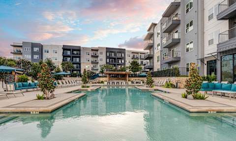 A large swimming pool in front of apartment buildings.