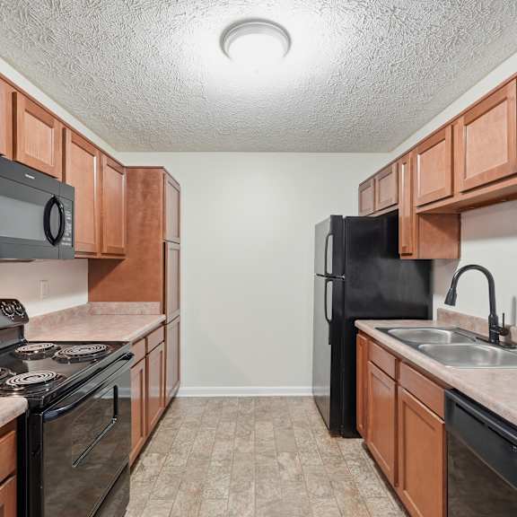 A kitchen with black appliances and brown cabinets.