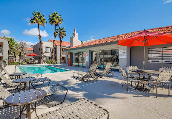 A poolside area with chairs and tables.