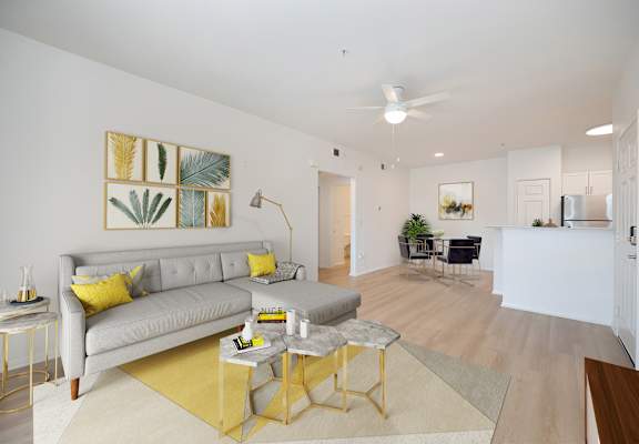 A living room with a grey couch and yellow pillows.