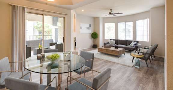 A modern living room with a glass table and grey chairs.