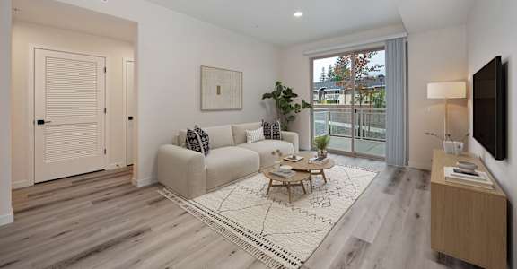 A living room with a couch, a coffee table, and a flat screen TV.