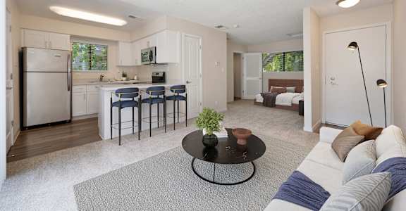 a living room with a couch and a table in front of a kitchen at Silverstone Apartments, Davis