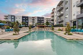 A large swimming pool in front of apartment buildings.