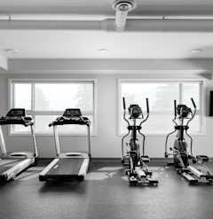 a gym with four treadmills and a flat screen tv