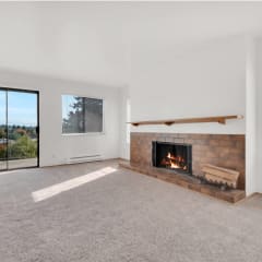 an empty living room with a fireplace and a large window