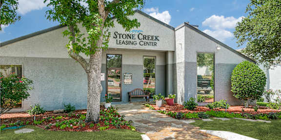 a stone creek leasing center with a tree in front of it