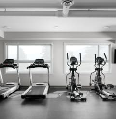 a gym with four treadmills and a flat screen tv