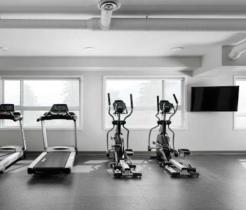 a gym with four treadmills and a flat screen tv